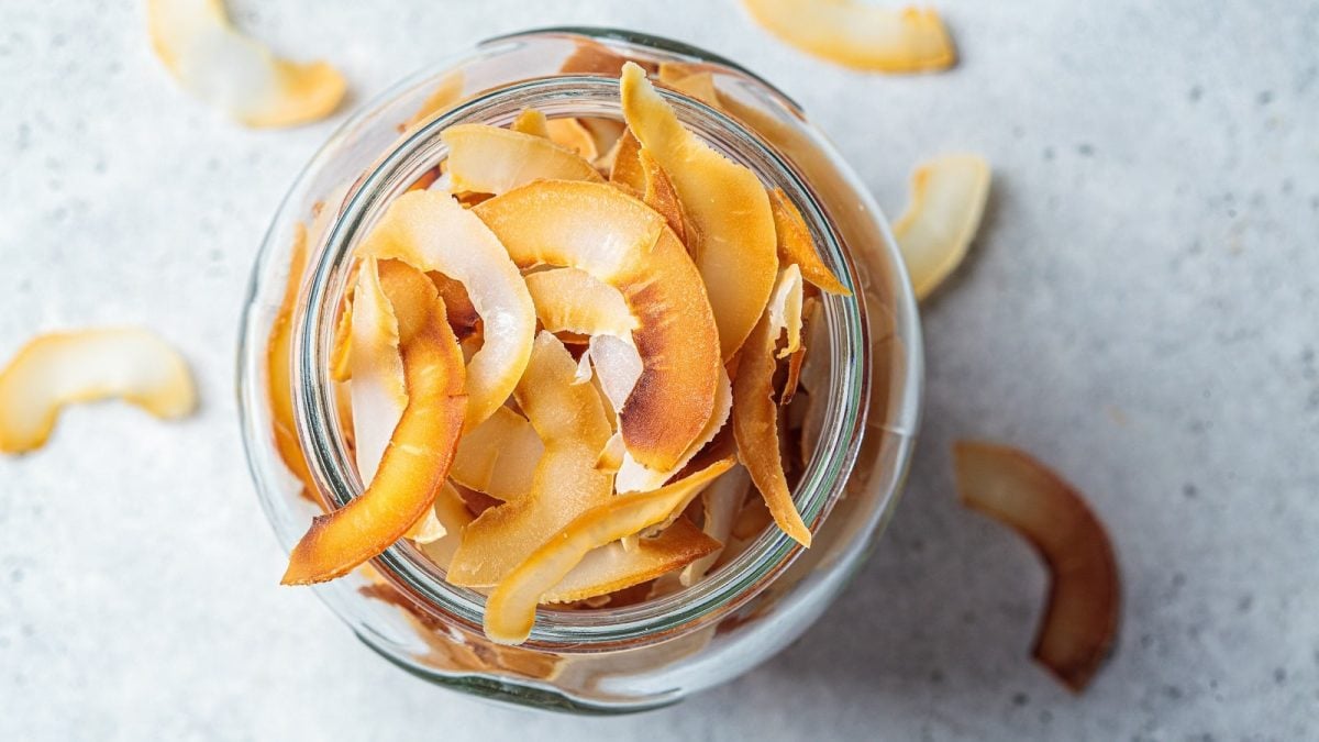 Ein Glas mit Zimt-Kokoschips auf einem weißen Untergrund.