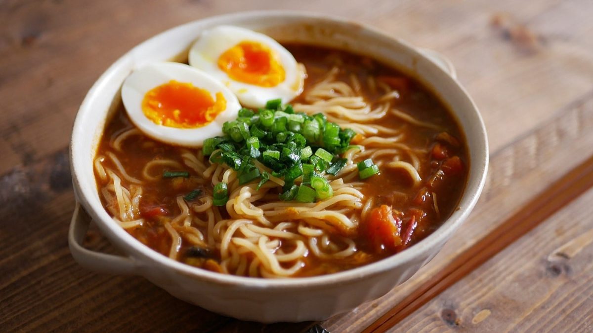 Eine Schüssel Curry Ramen auf einem braunen Holztisch.