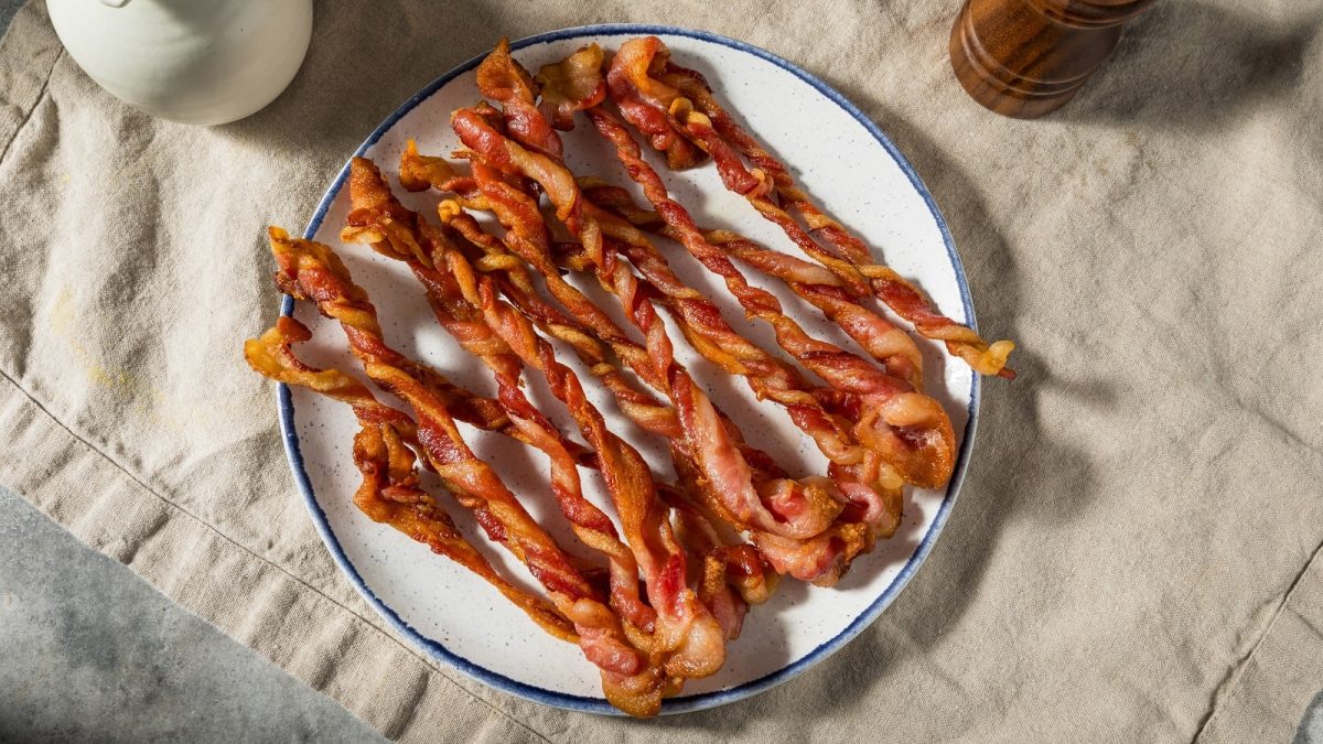 Ein weißer Teller mit Twisted Bacon auf einer beigen Tischdecke.