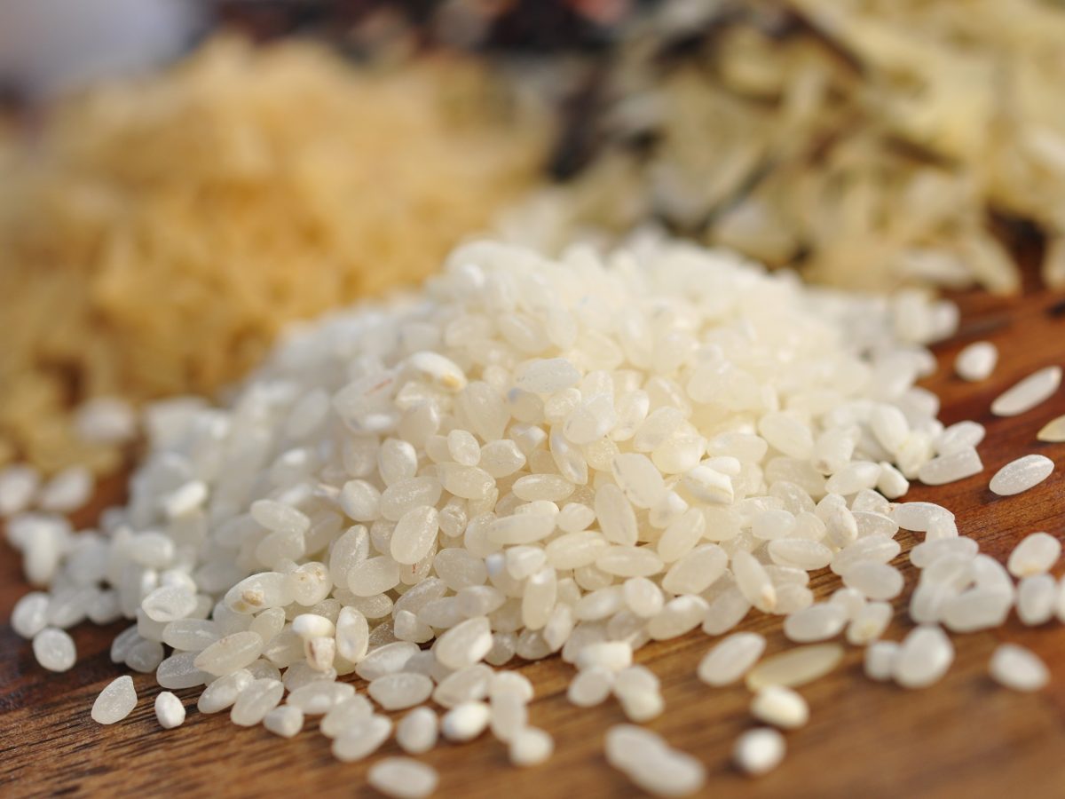 Risotto-Reis lose auf einem Untergrund aus Holz / Frontal