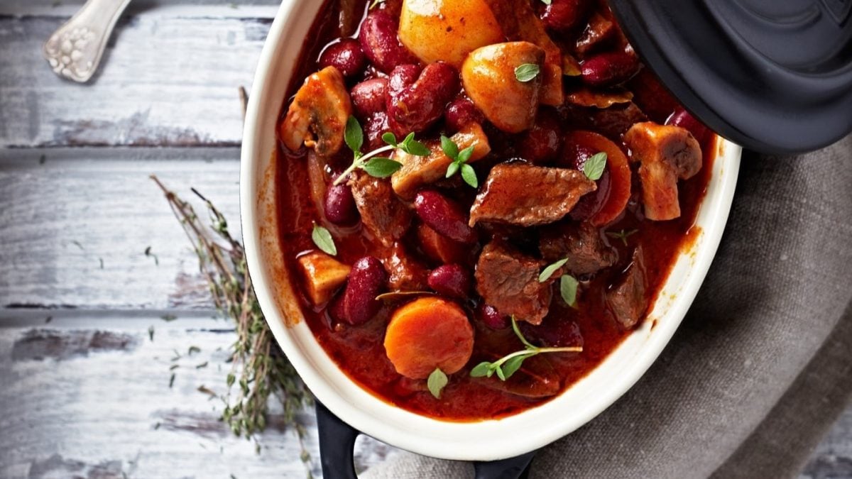 Rustikaler Hirtentopfs, reich gefüllt mit Fleisch, Pilzen und Kidenybohnen. Die Zutaten sind in einer herzhaften Sauce gekocht und präsentieren sich einladend in einem Kochtopf.