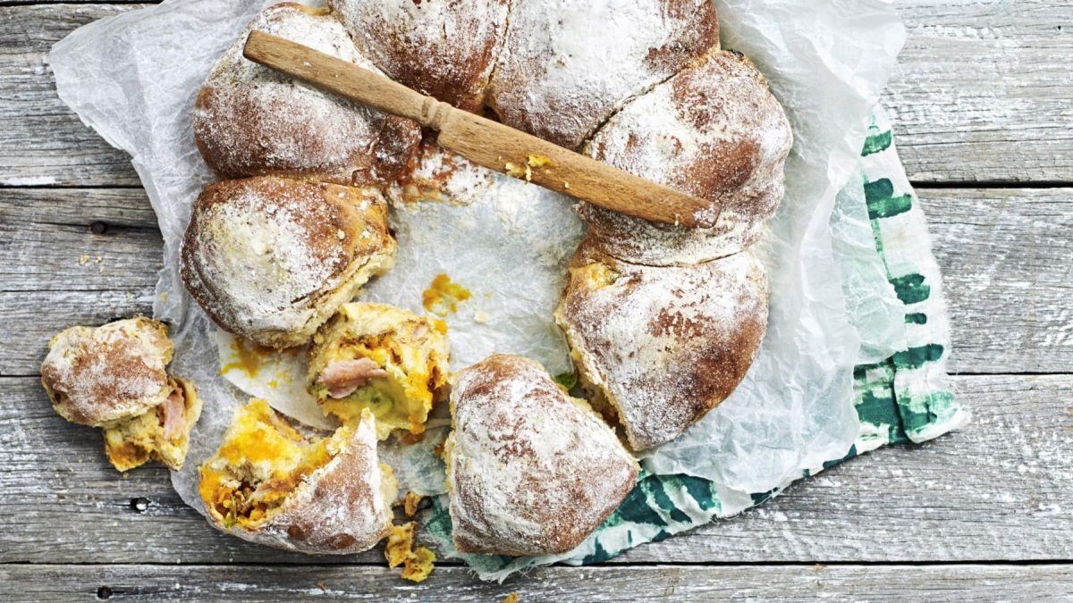 Gefüllte Zupfbrötchen mit Kürbis auf einem Holztisch.