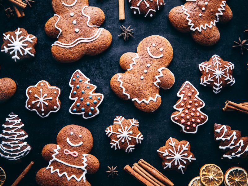Mehrere mit Zuckerguss verzierte Lebkuchen auf einem dunklen Untergrund direkt von oben fotografiert.
