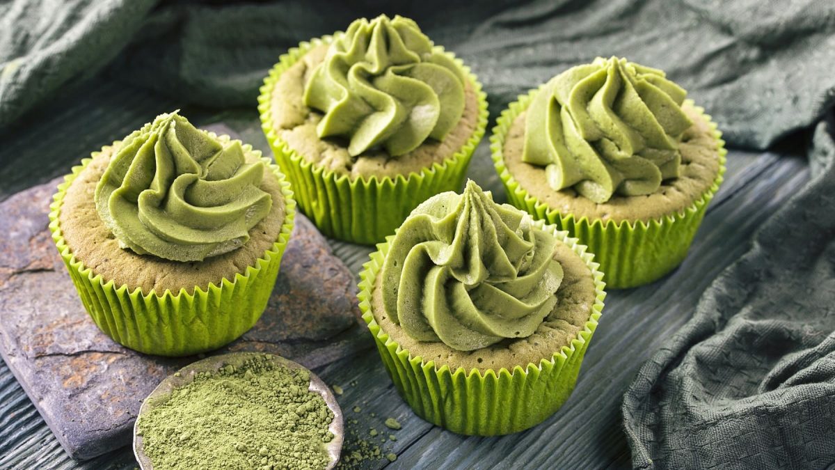 Einige Cucakes auf einem dunkelgrünen Tisch mit grüner Tischdecke. Alles von schräg oben fotografiert.