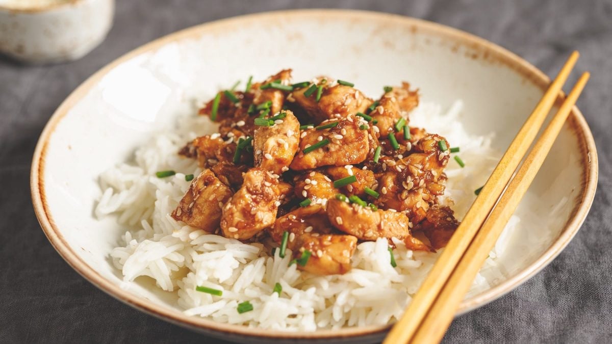 Ein weißer Teller mit dem Miso-Chicken und Reis auf einem grauen Untergrund.