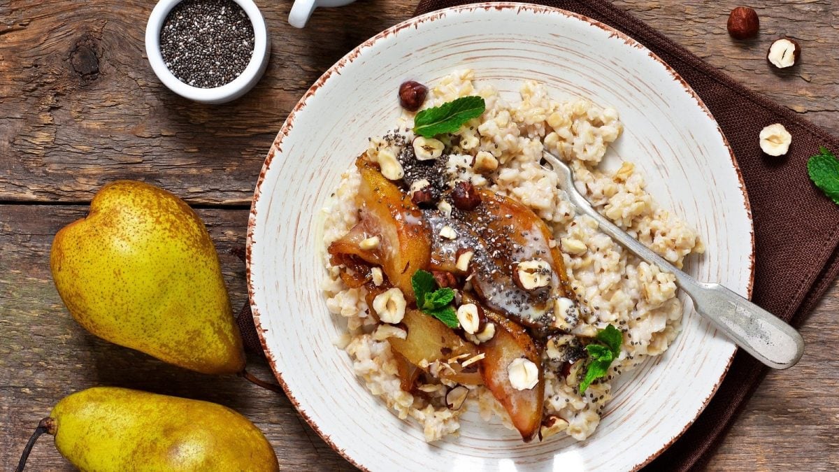 Ein weißer Teller mit karamellisiertem Birnen-Porridge auf einem braunen Holztisch.