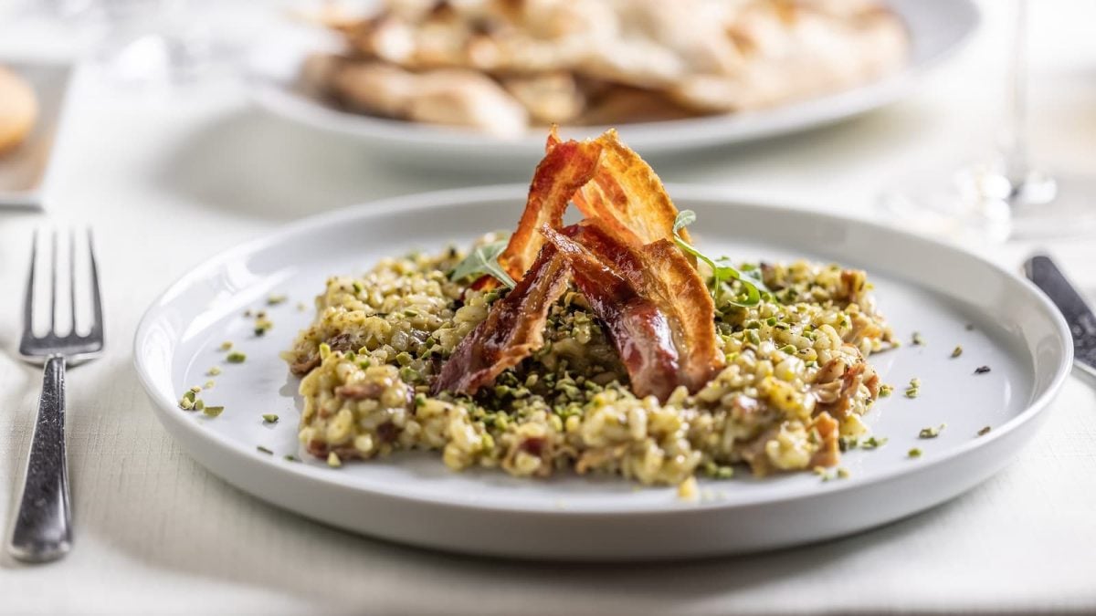 Ein grauer Teller mit Pistazien-Risotto darauf.