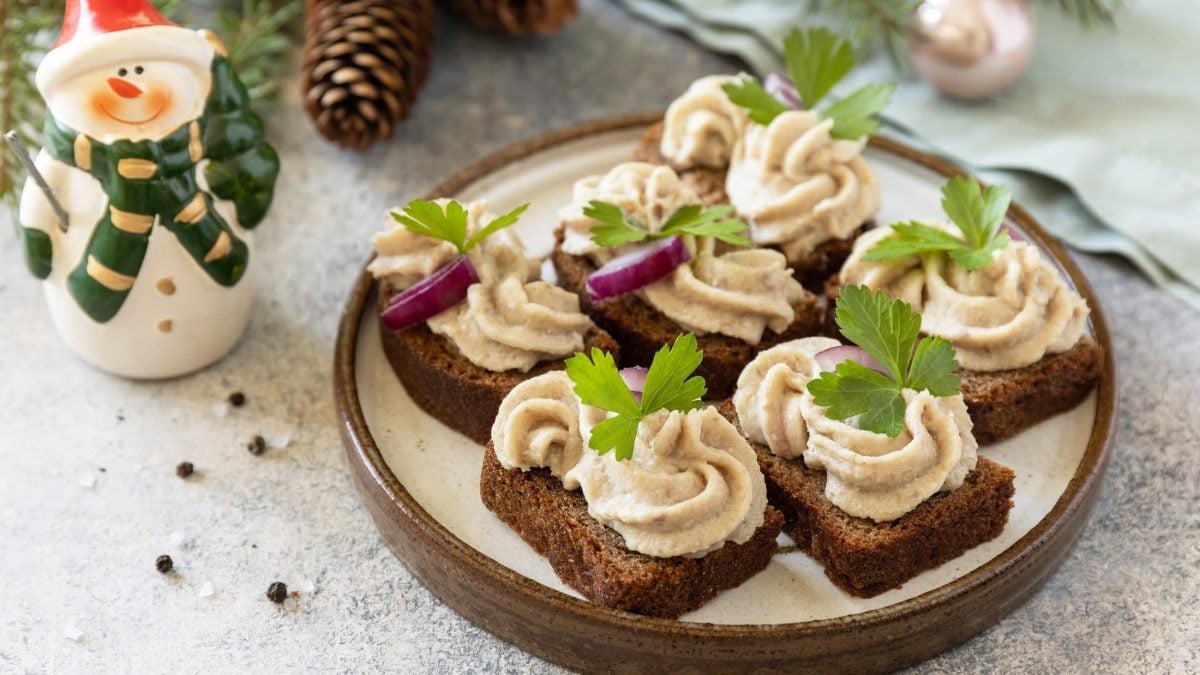 Draufsicht, schräg: Canapés mit Forellen-Creme auf einem beigen teller. Drum herum ist Weihnachts-Deko.