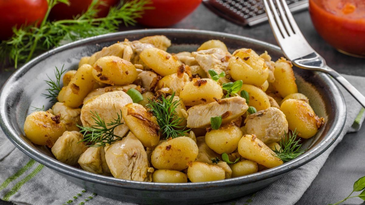 Draufsicht, schräg: eine auf einem Holztisch. Drumherum liegen eine Gabel und frische Kräuter.