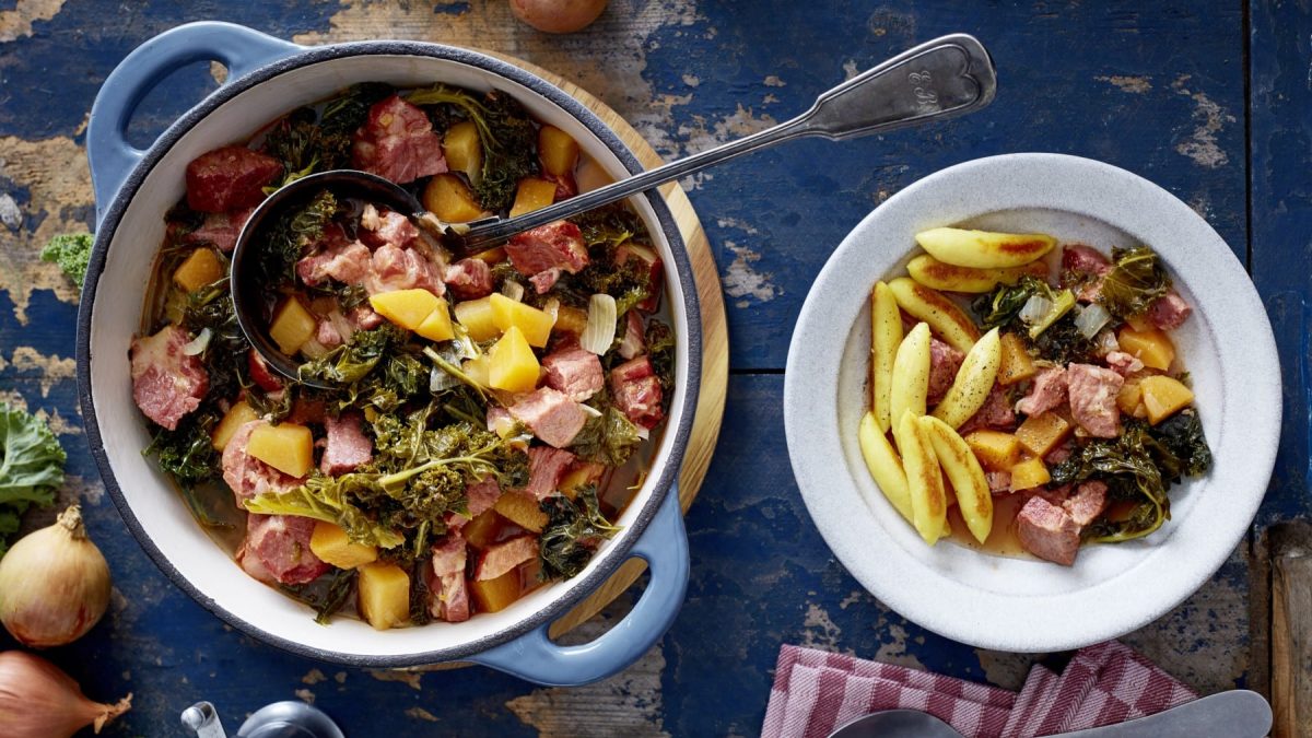 Ein Topf mit Kasseler-Gulasch, rechts davon ein Teller mit Kasseler-Gulasch und Schupfnudeln. Der Hintergrund ist blau.