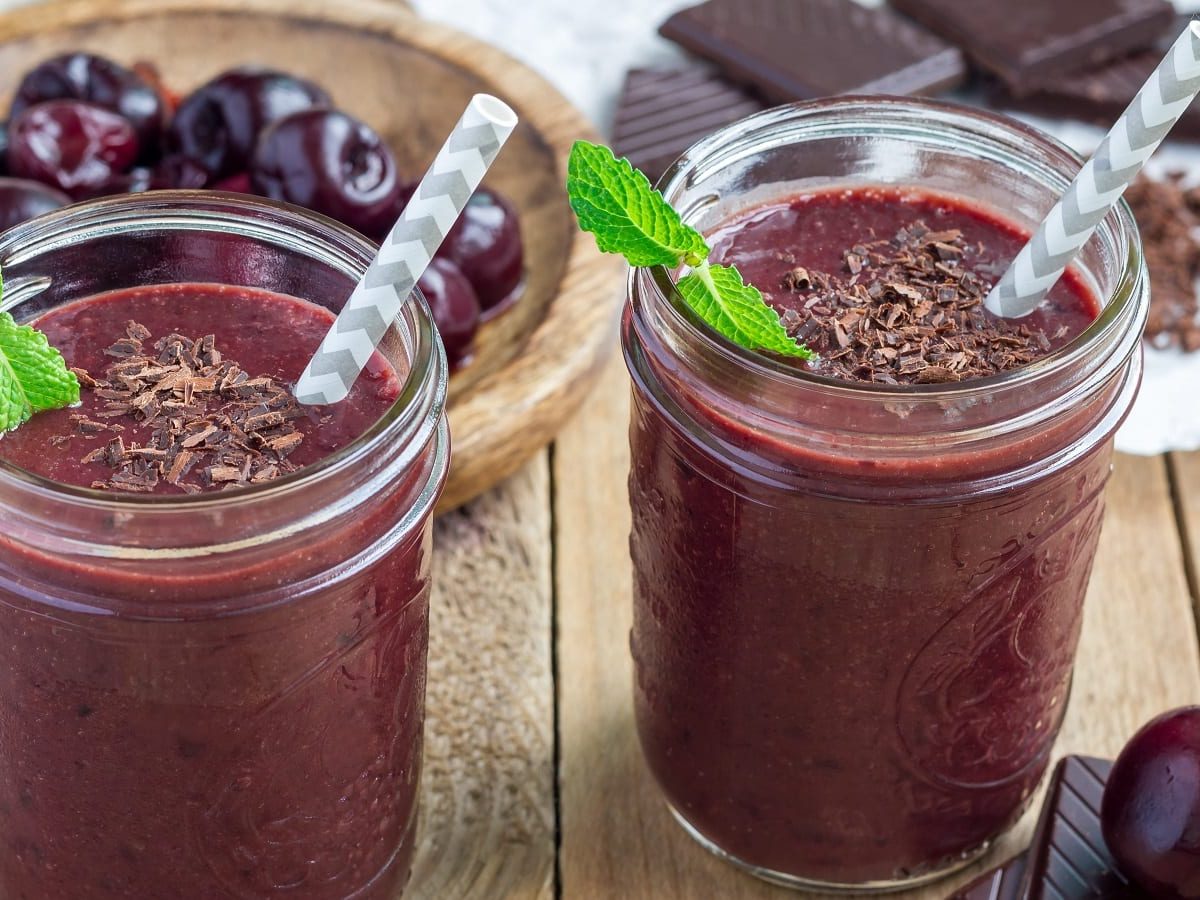 Zwei Gläser Schwarzwälder Kirsch-Smoothie auf einem Holztisch.