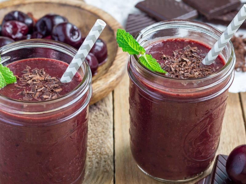 Zwei Gläser Schwarzwälder Kirsch-Smoothie auf einem Holztisch.