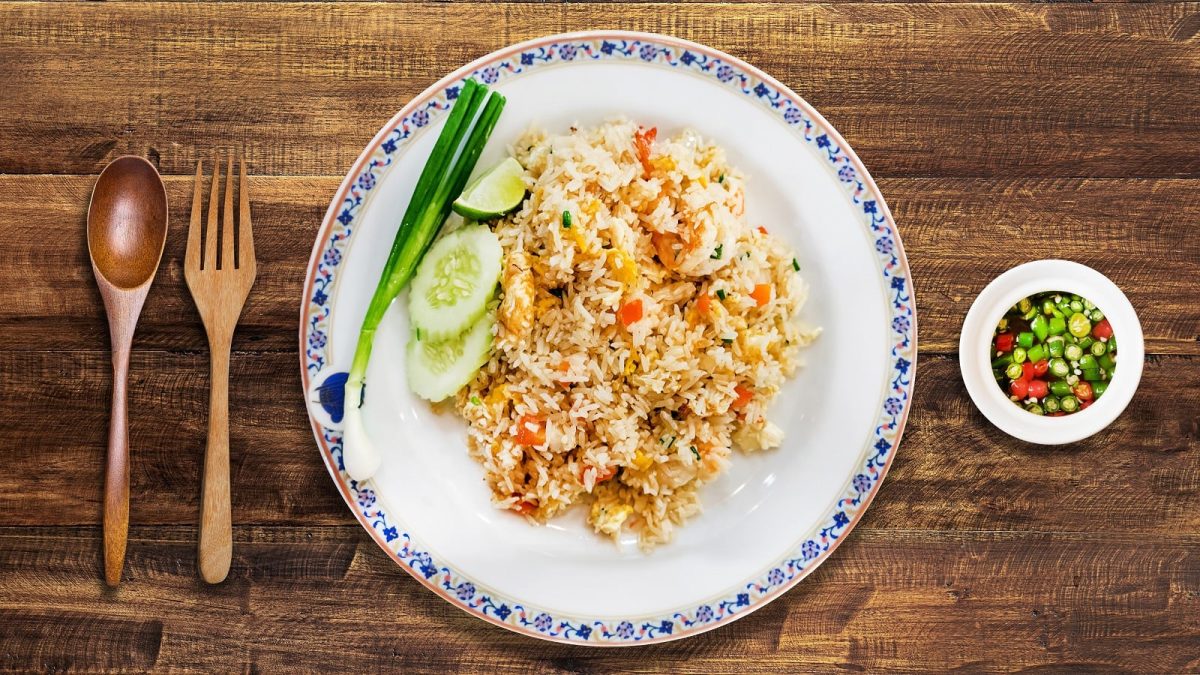Ein weißer Teller mit Khao Pad auf einem Holztisch.