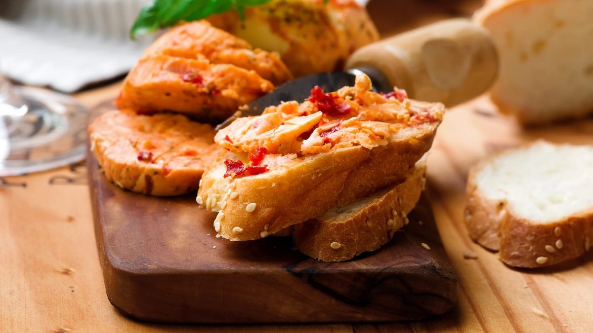 Ein Holzbrett mit Pizzabutter auf Brotscheiben.