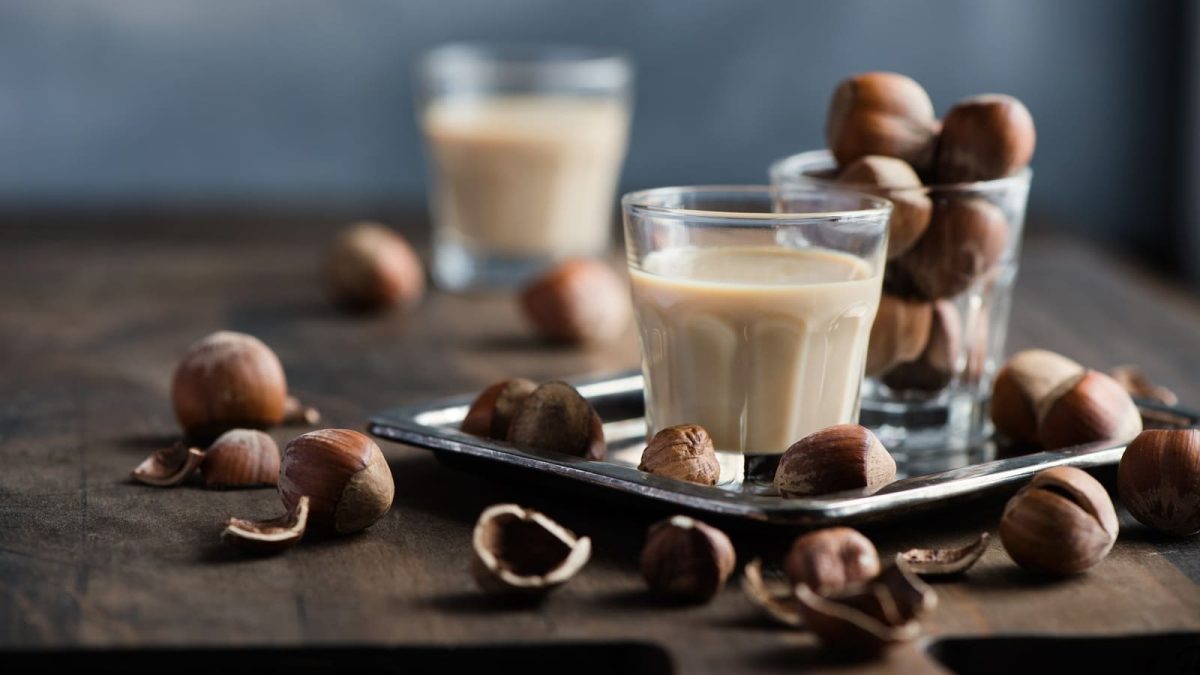 Zwei Shot-Gläser mit Giotto-Likör auf einem braunen Holztisch.
