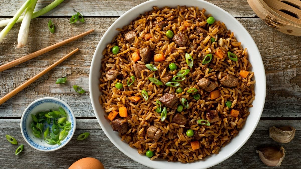 Ein Teller mit Beef Fried Rice auf einem Holztisch.