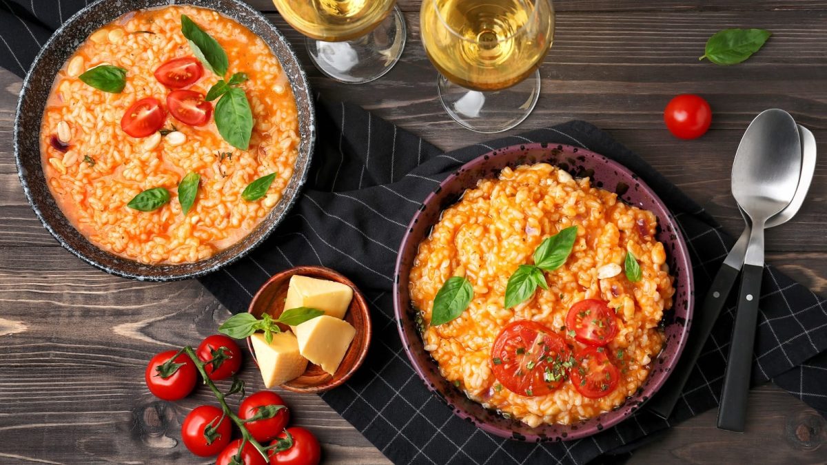 Zwei Teller mit Risotto alla pizzaiola auf einem Holztisch.