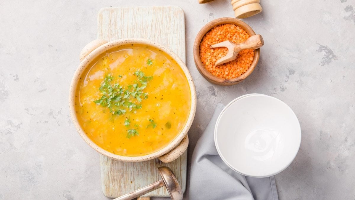 Eine Schüssel Kardamom-Linsensuppe auf einem hellgrauen Untergrund.