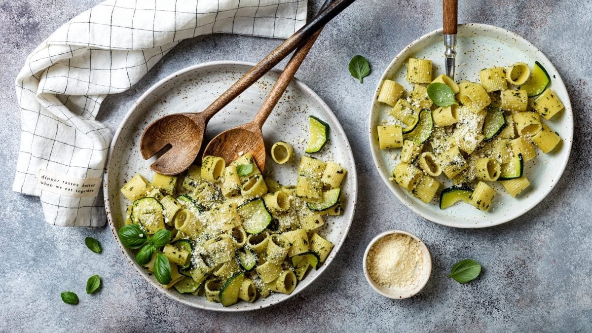 Zwei Teller mit Pasta e zucchine auf einem grauen Tisch