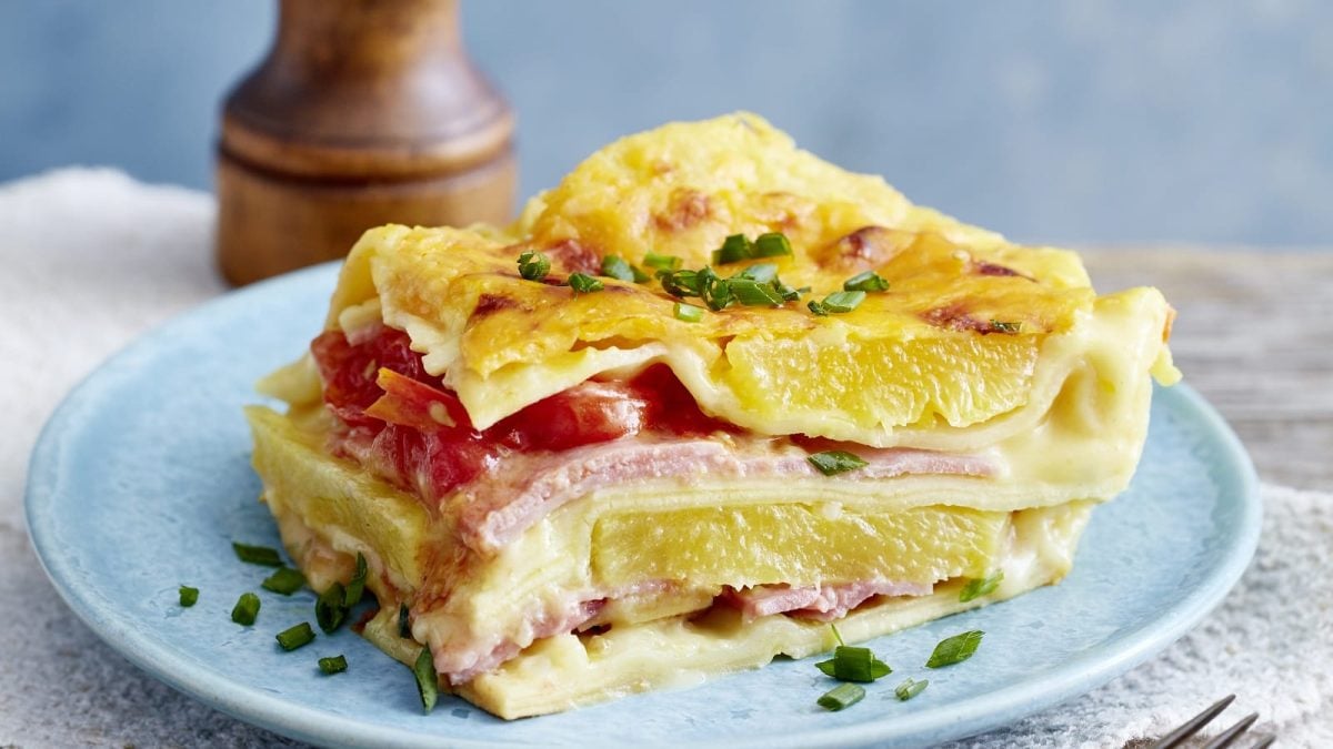 Ein hellblauer Teller mit einem Stück Lasagne Hawaii darauf.
