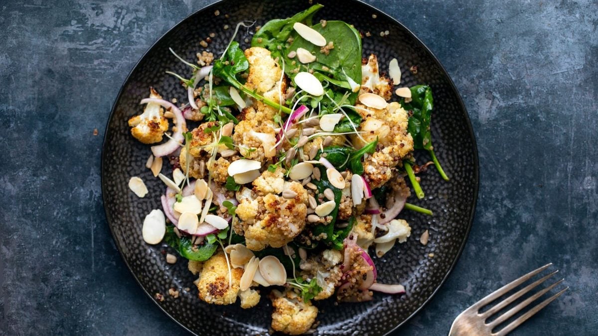 Ein schwarzer Teller mit dem Salat auf dunkelblauem Untergrund.