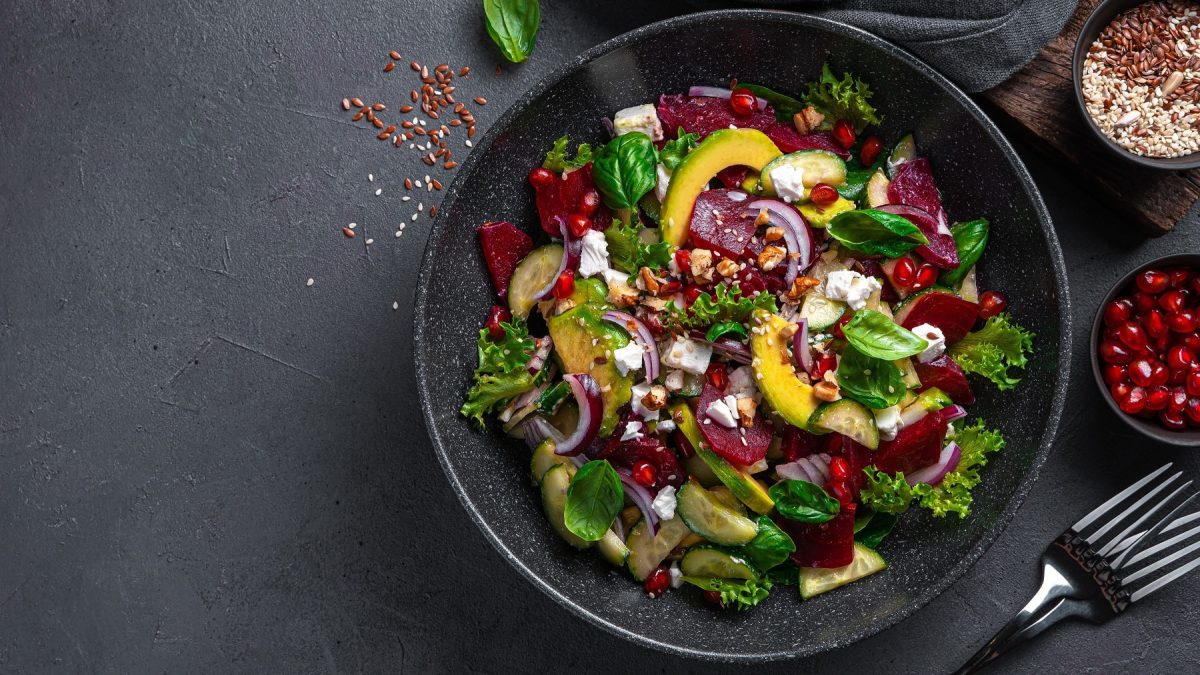 Ein schwarzer Teller mit dem Fitness-Salat direkt von oben auf schwarzem Untergrund fotografiert.