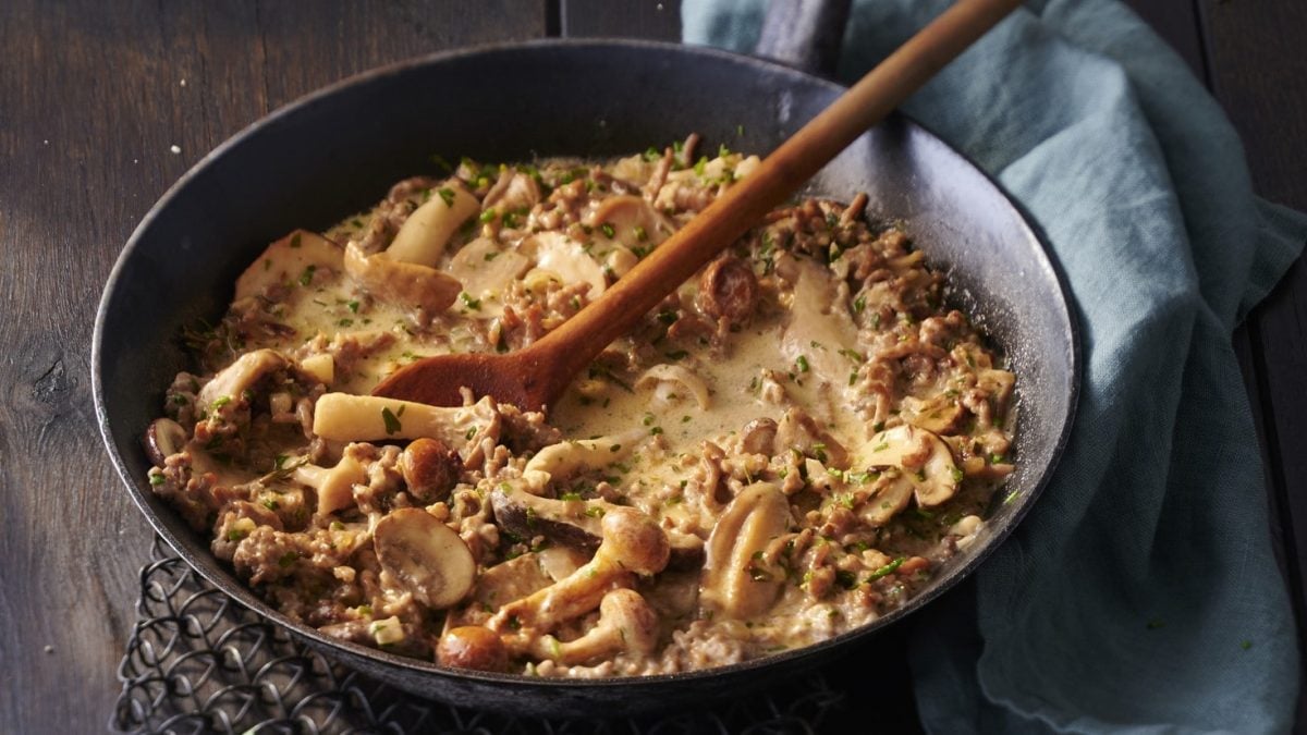 Pfanne mit gebratenem Hackfleisch und gemischten Pilzen in einer cremigen Sauce.