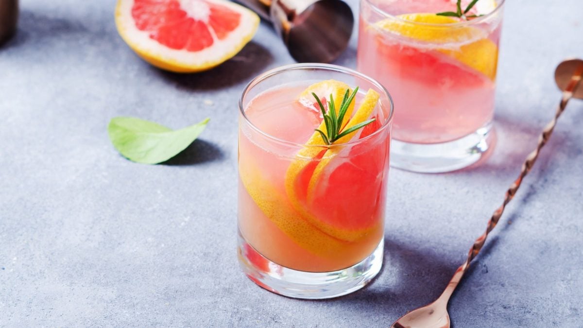 Zwei Gläser mit dem Pink Paloma auf grauem Untergrund. Daneben noch Barlöffel und Barmaß. Alles von schräg oben fotografiert.