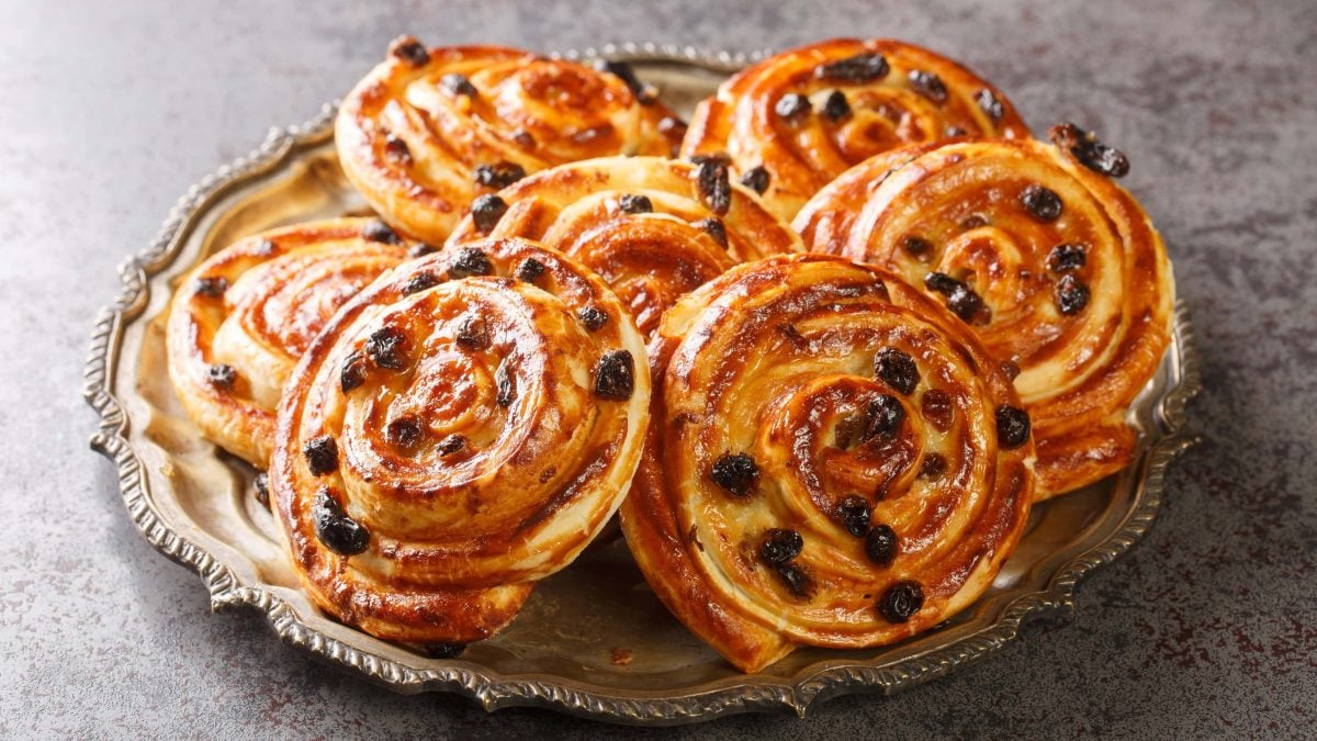 Mehrere Puddingschnecken auf einem silbernen Teller und grauen Untergrund. Alles von der Seite fotografiert.