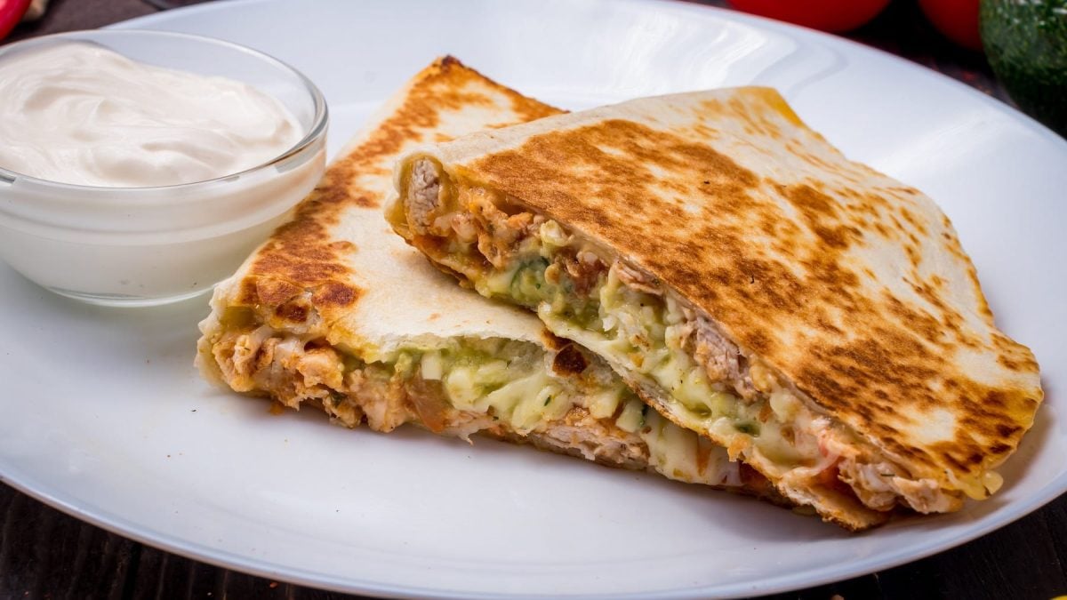 Zwei Stücke der Quesadilla auf einem weißen Teller von der Seite fotografiert.