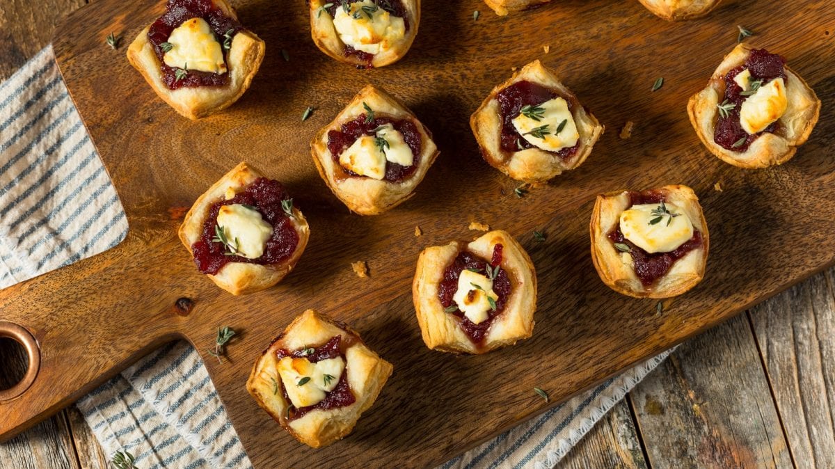 Eine Portion Cranberry-Ziegenkäse-Bites auf einem Holzbrett.