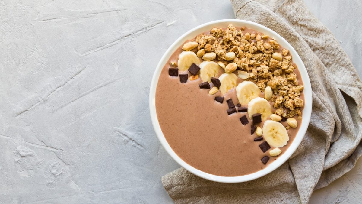 Kaffee-Smoothie-Bowl in einer weißen Schüssel auf einem weißen Hintergrund. Rechts ein beiges Geschirrtuch.