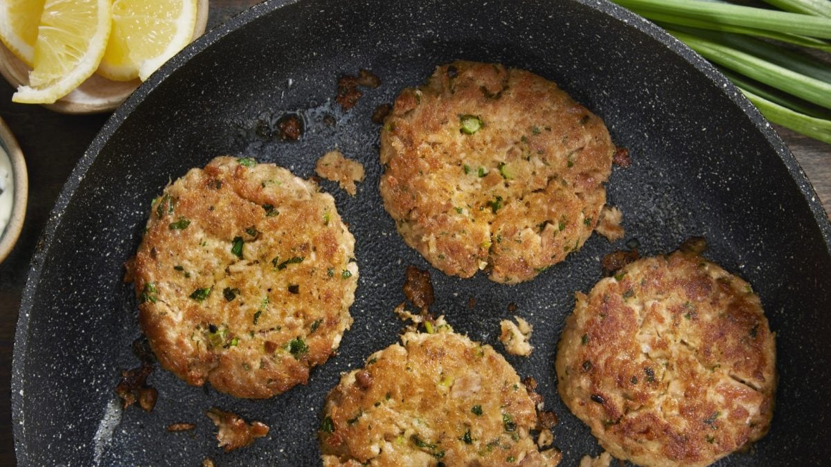 Vier Thunfisch-Küchlein in der Pfanne direkt von oben fotografiert.