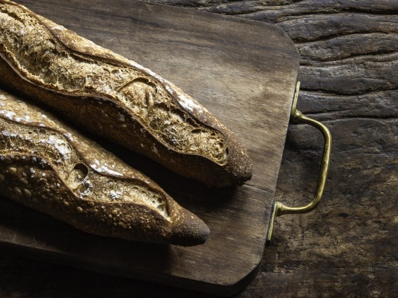 Baguettes auf einem dunklen Holzuntergrund. Alles direkt von oben fotografiert.