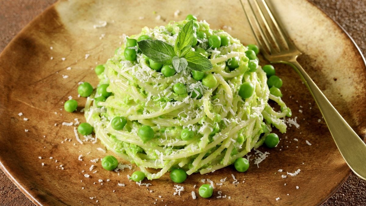 Draufsicht, schräg: Ein Teller Pasta e piselli. Neben dem Erbsen-Gericht für Gartenbesitzer liegt eine Gabel.