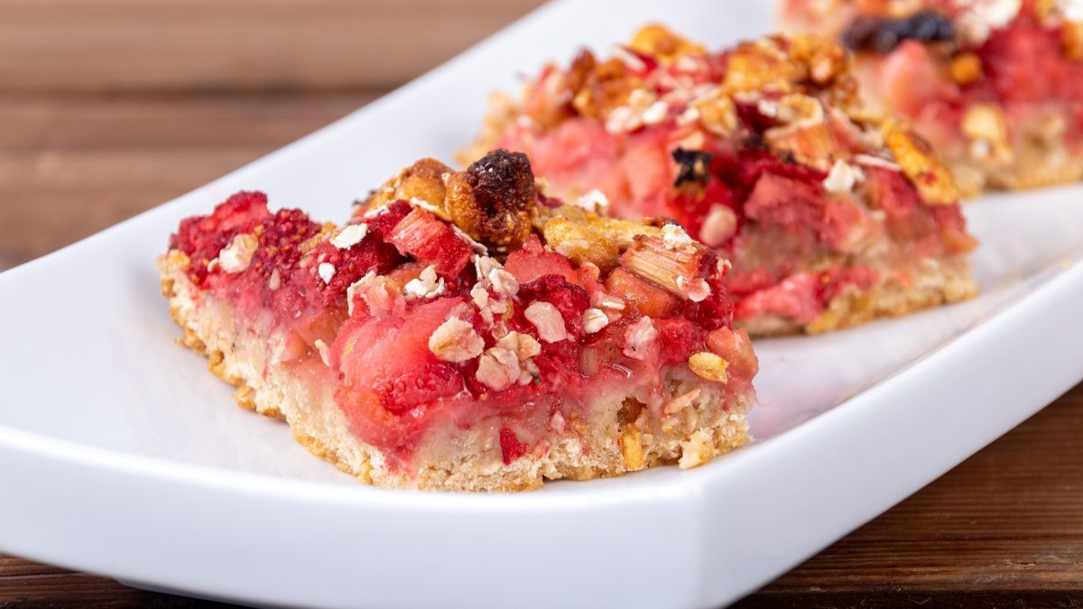Haferiegel mit Erdbeeren und Rhabarber in Nahaufnahme auf einem weißen Tablett.