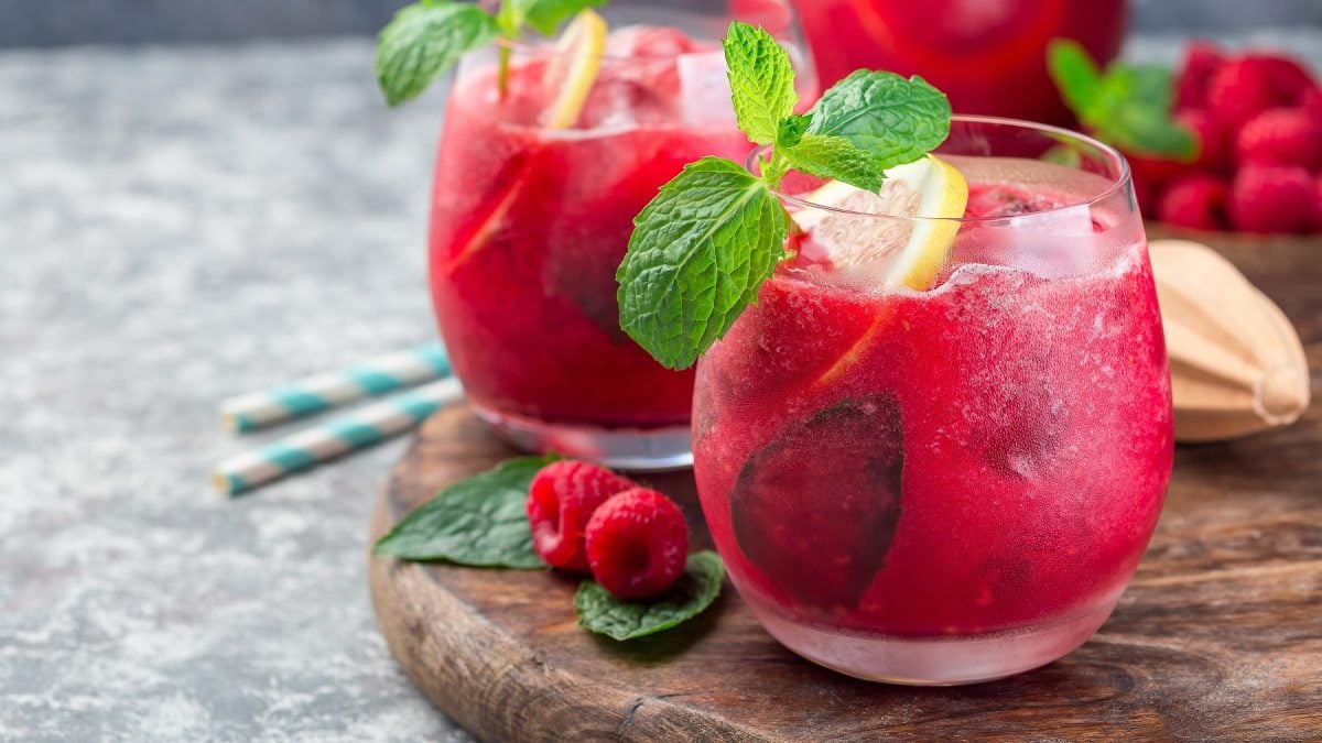 Himbeerlimonade in zwei Gläser, garniert mit frischer Minze und Zitronenscheiben.