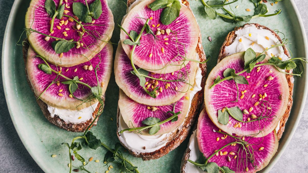 Stulle mit Wassermelonen-Rettich, Frischkäse und Micro-Greens auf einem grünen Teller.