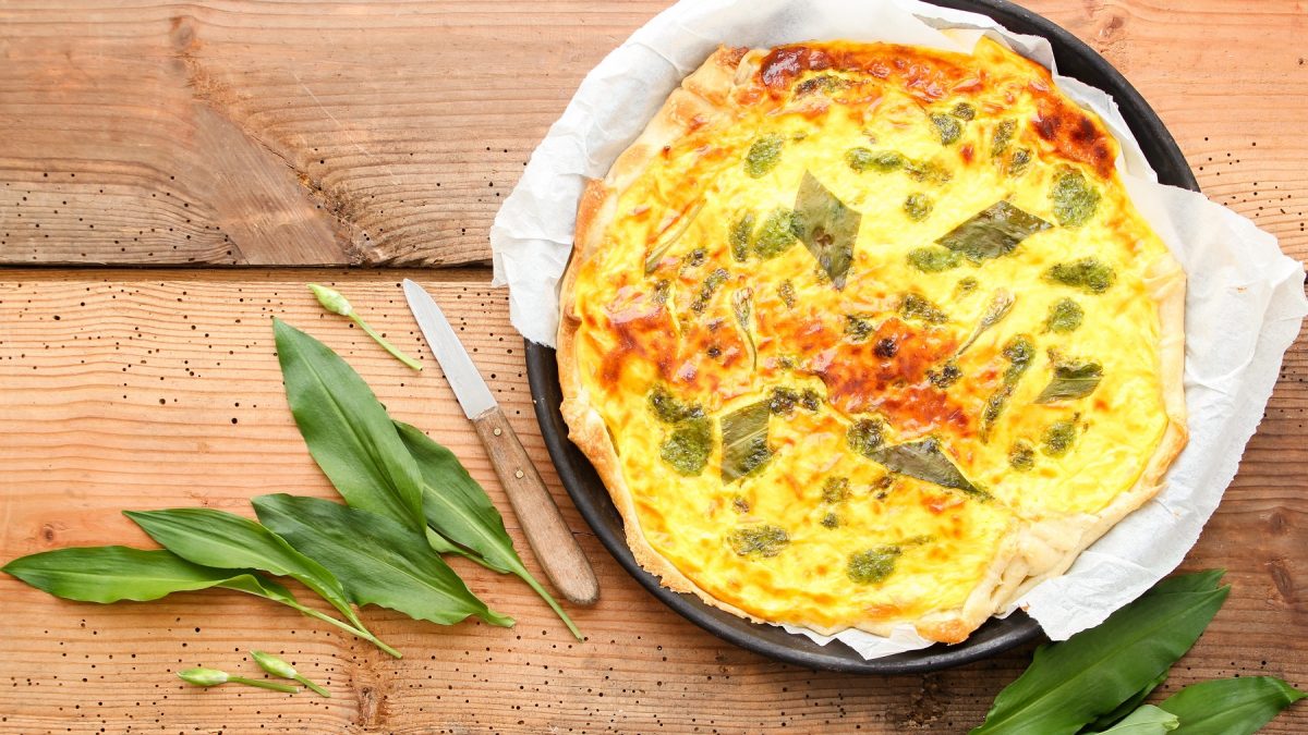 Draufsicht auf Wildkräuter-Quiche und frischen Bärlauch.