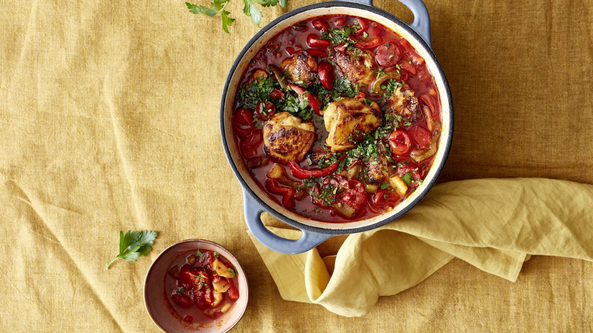 Andalusicher Chorizo-Hähnchen-Pott in einem Suppentopf. Daneben Schüssel mit dem Eintopf.