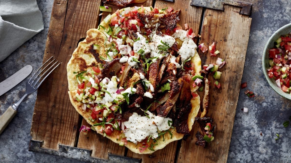 Austernpilz-Shawarma auf einem hölzernen Schneidebrett auf grauem Hintergrund.