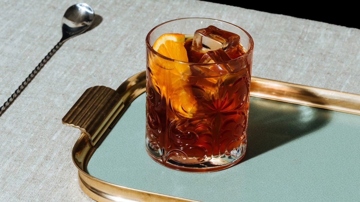 Averna Sour auf einem blauen Tablett. Daneben ein Barlöffel.