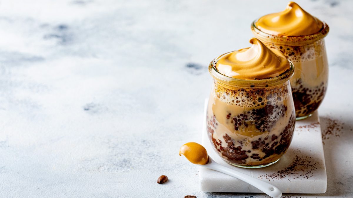 Dalgona Chia-Pudding in zwei kleinen Weck-Gläsern vor einem hellen Hintergrund.