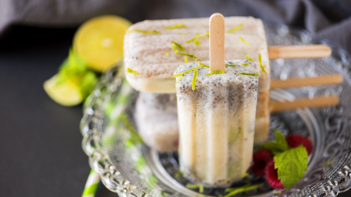 Selbstgemachte Eiscreme am Stiel mit Zitronenzesten und Minzblättern, serviert auf silbernem Teller.