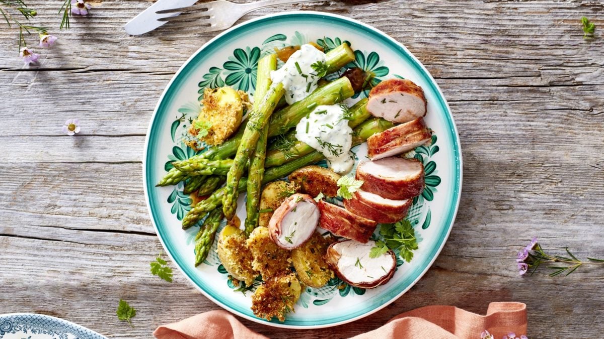 Filet-Spargel-Pfännchen: Spargel, Kartoffeln und Schweinefilets auf blauem Teller mit Holzuntergrund.
