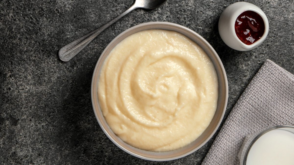 Eien weiße schale mitd em Grießpudding und einem kleinen Schälchen mit der Kirschgrütze auf grauem Untergrund. Alles direkt von oben fotografiert.