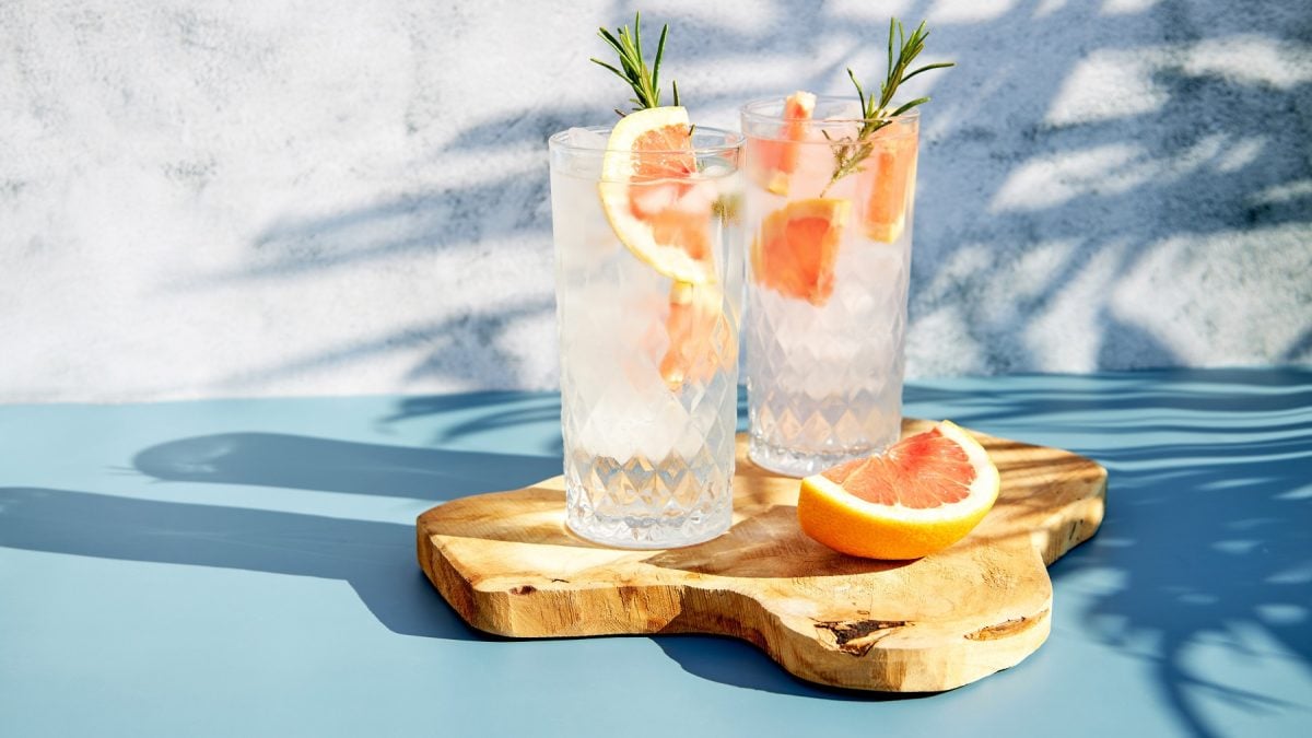 Lacascara Spritz in zwei Highballgläsern mit Grapefruit und Rosmarinzweigen.
