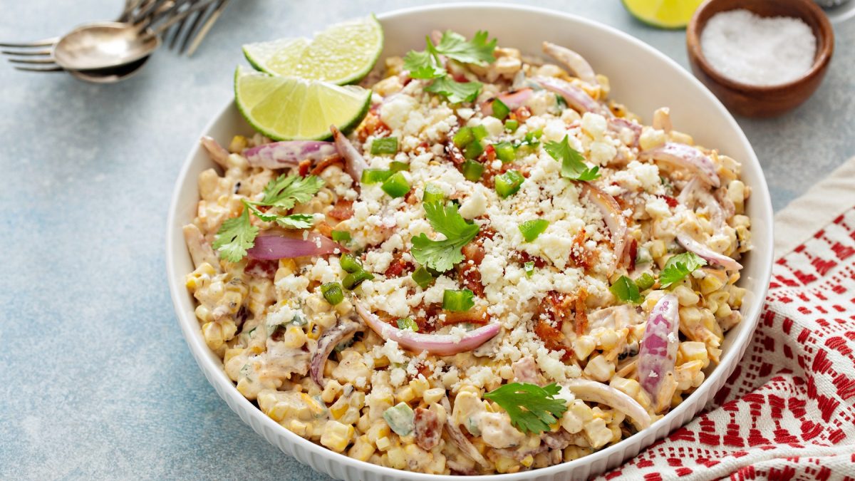 Maissalat in einer Schüssel. Getoppt mit Limettenspalten und Petersilie.