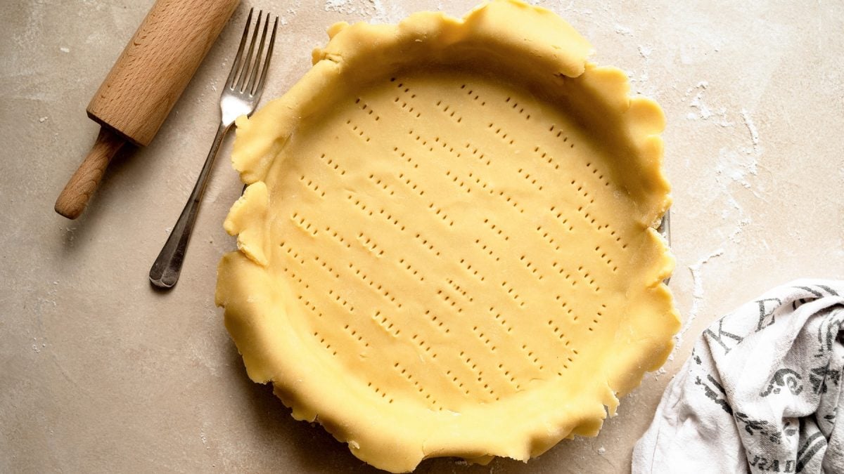 Mürbeteig in einer Tarteform, der schon eingestochen wurde.