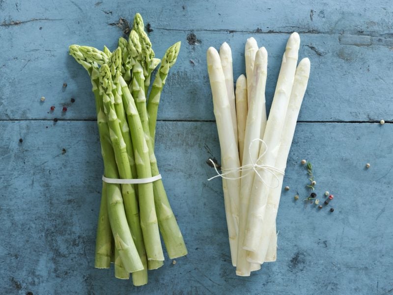 Jeweils ein Bund weißer udn grüner SPargel auf einem blauen Untergrund. Alles direkt von oben fotografiert.